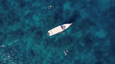Sürat teknesi ve yüzen turistlerle turkuaz mavi su denizi, havadan insansız hava aracı görüntüsü. Doğada bir gemi okyanus manzarası. Yaz tatili seyahati, tatil beldesi, turizm.