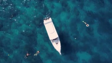 Sürat teknesi ve yüzen turistlerle turkuaz mavi su denizi, havadan insansız hava aracı görüntüsü. Doğada bir gemi okyanus manzarası. Yaz tatili seyahati, tatil beldesi, turizm.