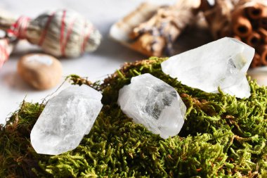 Arka planda beyaz adaçayı lekeleri olan yeşil yosun üzerinde üç kuvars kristali. 