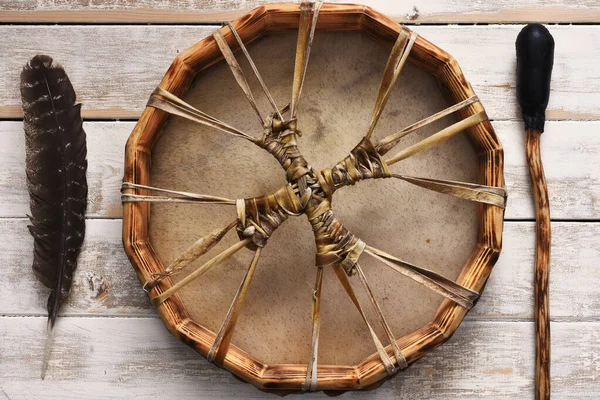 Beyaz yıkanmış bir masanın üzerinde kutsal tüy ve deriden yapılmış meditasyon davulunun karışık bir görüntüsü.. 