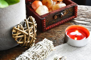 Citrine ve Carnelian kristalleriyle dolu küçük ahşap bir kutu. Kırmızı mum ve beyaz adaçayı demetleri.. 
