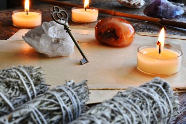 Net bir kuvars kristal kümesine dayanan eski bir pirinç anahtarın üç yanan mumla görüntüsü.. 