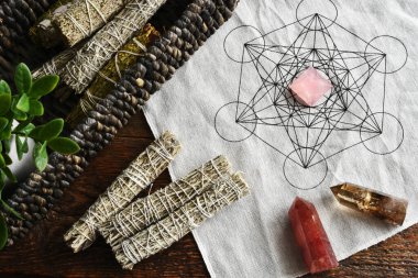 Kutsal geometri şebekesi kumaşı ve gül kuvars piramidi ile beyaz adaçayı leke demetlerinin üst görünümü!  