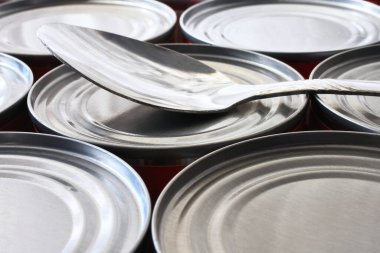 Birkaç konserve kutusunun üzerinde duran metal kaşığın yakın plan görüntüsü.. 