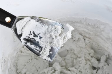 Duvardaki alçı alaşımlı bir kovanın üzerindeki duvardaki çamurla kaplı bir spatula resmi..