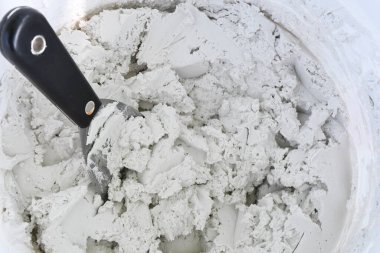 Duvardaki alçı alaşımlı bir kovanın üzerindeki duvardaki çamurla kaplı bir spatula resmi..