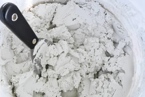 Duvardaki alçı alaşımlı bir kovanın üzerindeki duvardaki çamurla kaplı bir spatula resmi..