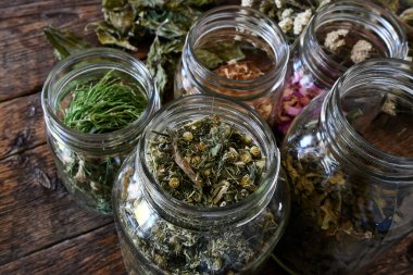 A top view image of several clear jars filled with organically grown medicinal dried herbs. 