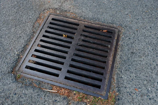 An abstract image of a rusted metal storm water drain will debris around it.