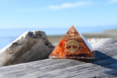A close up image of an carnelian orgonite energy generating pyramid with the tree of life symbol.  clipart