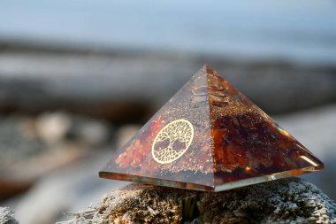 A close up image of an carnelian orgonite energy generating pyramid with the tree of life symbol.  clipart