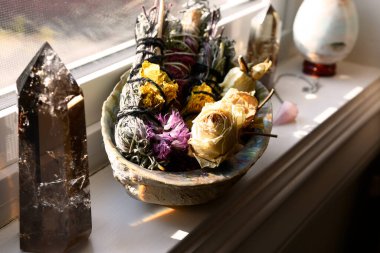 Leke çubukları ve beyaz pencere eşiğinde dinlenen kurumuş gül tomurcuklarıyla dolu bir deniz kulağı kabuğunun yakın plan görüntüsü.. 