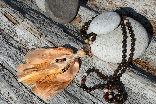 一条木制珠子玛拉项链和两块堆成的Zen石头在一块浮木上的特写图片 — 图库照片