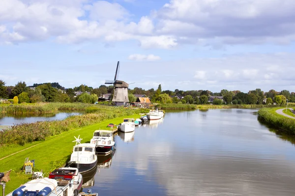 Dutch wind mill at river with little boats — Stock Photo, Image