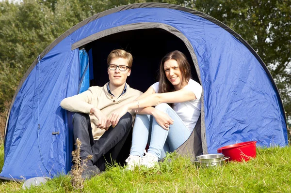 Young man and woman camping with blue tent Royalty Free Stock Photos