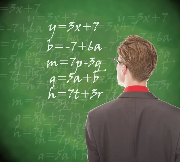 Young student looking at chalkboard with mathematics — Stock Photo, Image