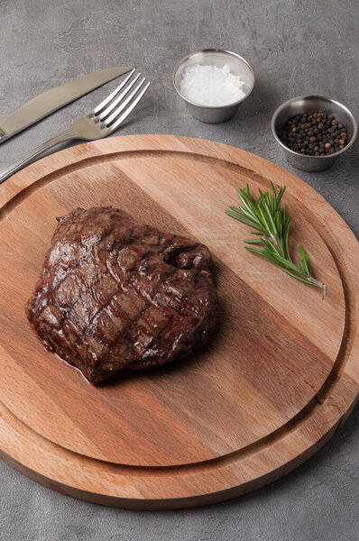 Tasty veal steak with rosemary on a wooden board