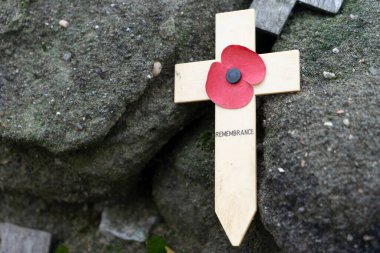Lest we forget -  Remembrance poppy on a wooden cross symbol of the first World War WOI at old trenches near Ypres Belgium