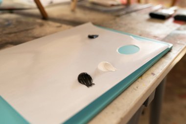 Some dots of blue black and white paint on a palette ready for painting by an artist
