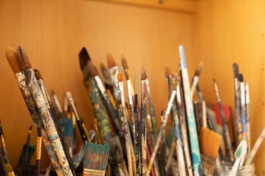 Many paintbrushes  in pots for art and artist in a bookcase