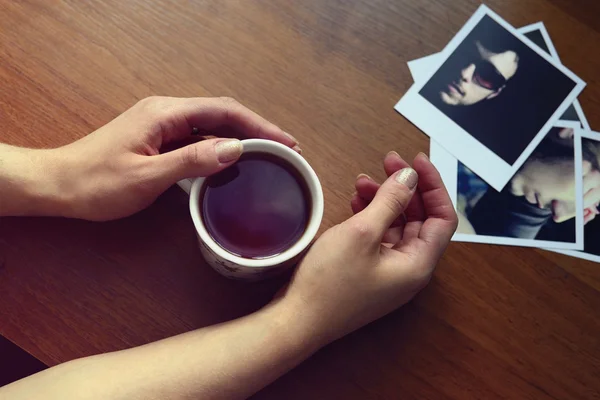 bir fincan çay ve fotoğraflar ile tutan eller