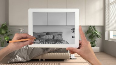 Tablete el ele tutuşup çizim yapmak klasik beyaz ve ahşap yatak odası detaylarını gösteriyor. Arka planda gerçekten bitmiş iç mimari tasarım sunumu