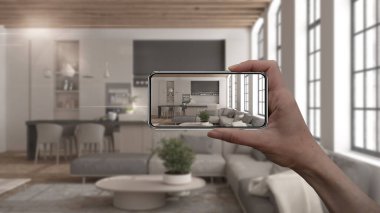 El ele tutuşan akıllı telefon, AR uygulaması, gerçek evde mobilya ve iç tasarım ürünleri simülasyonu, mimar tasarım konsepti, bulanık arka plan, modern oturma odası ve mutfak