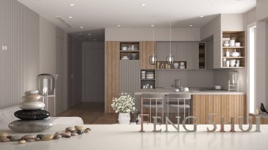 Beyaz masa rafı, çakıl taşı dengesi ve 3D harflerle modern ahşap mutfak, yemek masası ve koltuklar, zen konsepti iç tasarım üzerine feng shui yazılıyor.