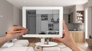 Modern oturma odası ve mutfak detaylarını gösteren tablet üzerindeki el ele tutuşmalar ve çizimler CAD çizimleri. Arka planda gerçekten bitmiş iç mimari tasarım sunumu