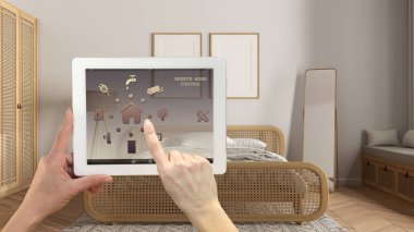 Dijital tablette akıllı uzaktan kumanda sistemi. Uygulama simgeleri olan aygıt. Modern ahşap yatak odası, rattan yatak, çerçeve modeli, arka planda, mimari iç tasarım.