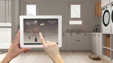 Dijital tablette akıllı uzaktan kumanda sistemi. Uygulama simgeleri olan aygıt. Modern beyaz ve ahşap çamaşır odası, balkon odası, arka plan, mimari iç tasarım.
