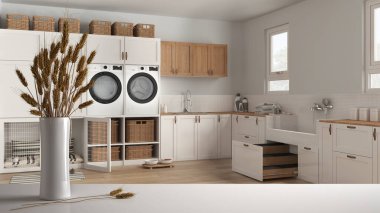 Beyaz masa üstünde ya da rafta pipetler, kuru bitkiler, süs, kulaklar, çarşaf, vazo dalları, köpek banyosu ve modern iç tasarımı olan hayvan dostu çamaşır odası.