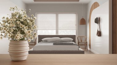 Ahşap masa ya da rafın üstünde çömlek vazosu, papatyalar, yabani çiçekler, modern yatak odasının üzerinde çift yatak ve pencere, Venedik panjurları, minimalist iç tasarım konsepti.