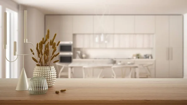 Wooden table, desk or shelf close up with ceramic and glass vases with dry plants, straws over blurred view of modern kitchen with dining table, minimalist interior design concept