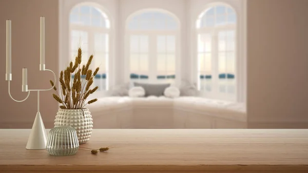 Wooden table, desk or shelf close up with ceramic and glass vases with dry plants, straws over blurred view of modern panoramic window with bench, minimalist interior design concept
