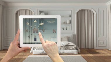 Dijital tablette akıllı uzaktan kumanda sistemi. Uygulama simgeleri olan aygıt. Klasik yatak odası, arka planda küflenmiş duvarlar, mimari iç mimari tasarım.