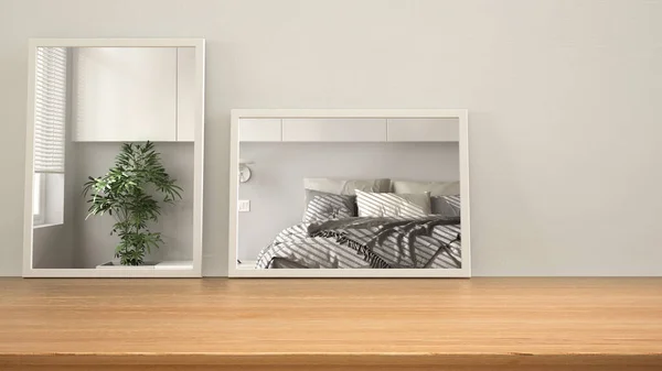 Minimalist mirrors on wooden table, desk or shelf reflecting interior design scene. White bedroom with double bed and potted plant. Modern background with copy space