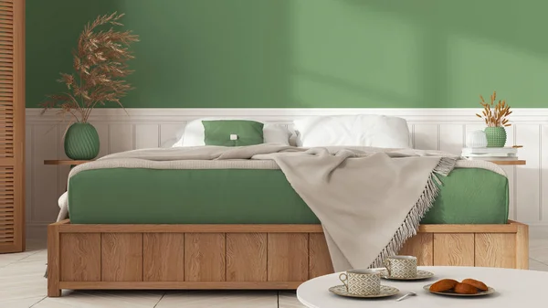 Wooden minimalist bedroom in white and green tones. Mater bed with blanket close up with copy space. Parquet floor, table with tea cups, breakfast with cookies. Interior design