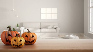 Ahşap masaya oyulmuş Cadılar Bayramı balkabakları. İç dizayn sahnesinde sonbahar dekorasyonu. Kanepe ve çerçeve modeliyle modern oturma odası