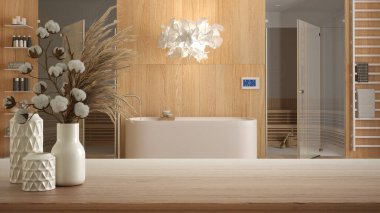 Ahşap masa, masa ya da raf küvetli kaplıca banyosunun üzerinde pamuk çiçekleri olan seramik vazolarla kaplan iç mimari konsepti.