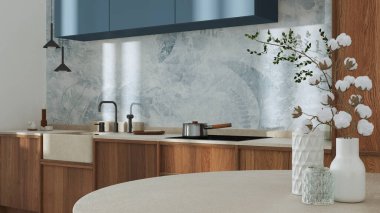 Japandi trendy wooden kitchen and dining room in white and blue tones. Close up on table with cotton flowers, wallpaper, cabinets and marble top. Minimalist interior design