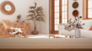 Boş ahşap masa, masa ya da rafta bohem ahşap oturma odasının bulanık görüntüsü. Yastıklı beyaz kanepe, modern iç tasarım konsepti.