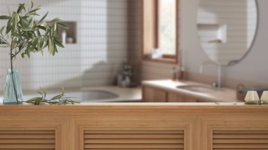 Ahşap masa üstü, dolap, panel ya da rafta kepenkler kapalı. Vazoda ve mumlarda zeytin dalı. Beyaz modern japandi banyosu ve iç tasarımı ile bulanık arkaplan