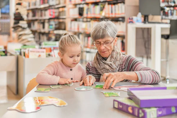 Cucu dan nenek mengumpulkan teka-teki di perpustakaan kota — Stok Foto