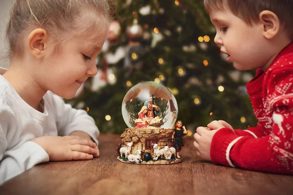 Children looking at a glass ball with a scene of the birth of Jesus Christ — ストック写真