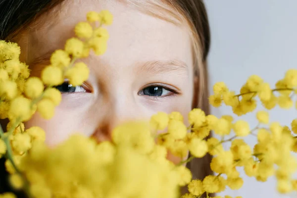 Mädchen hält Mimosen auf weißem Wandhintergrund — Stockfoto