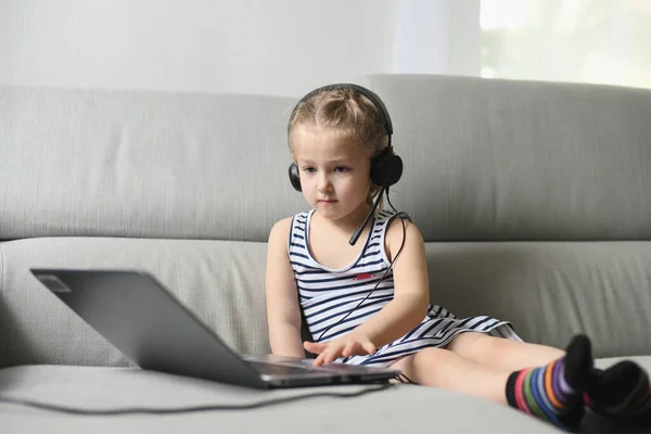 Chica en auriculares jugar con la computadora de los padres — Foto de Stock