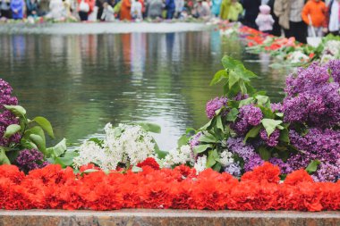 Kırmızı karanfil ve leylak suya yakın mermer bir askeri anıt üzerinde