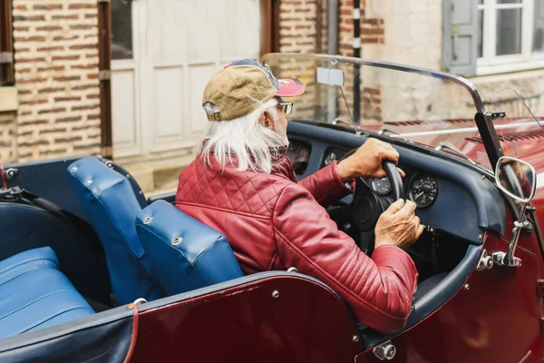 Abuelo de pelo gris conduce un coche vintage con interior de cuero — Foto de Stock