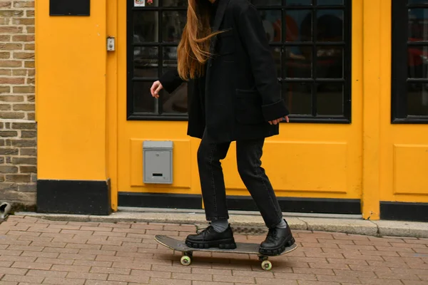 Een Meisje Bij Een Gele Muur Met Een Skateboard — Stockfoto